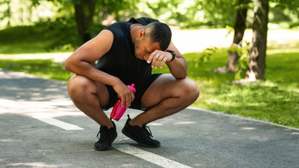 Exhausted black sportsman resting on jogging track after intensive workout, empty space