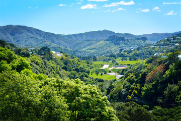 Naklejka na ściany i meble Cosy valley between green mountains in suburbuan Wellington, New Zealand. Bright sunny day in spring