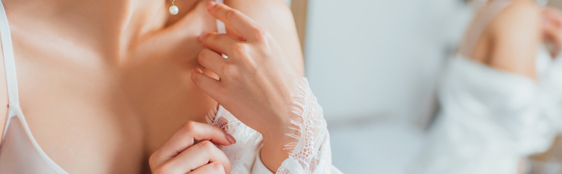 Horizontal image of bride in bra touching silk robe at home