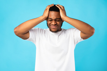Naklejka premium Black Man Suffering From Headache Touching Head, Blue Background