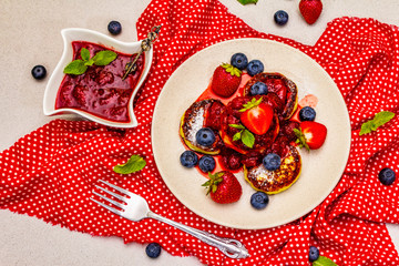 Cottage cheese pancakes with fresh berries and strawberry sauce. Healthy breakfast concept on stone background