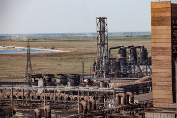 Old abandoned soviet metallurgy factory buildings, pipelines and rusted chimneys on blue sky and...