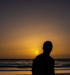 silhouette of a man sitting on the beach