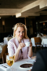 Beautiful businesswoman dressed in the suit drinking coffee. Businessman and businesswoman enjoying in the restaurant.