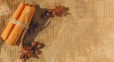 Flat lay of cinnamon sticks, coffee beans, star anise lie on background of sacked napkins with copy space for text. Close-up photo in warm toned. Spice concept, menu layout for coffee shop.