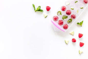 Ice tray with berries, lime and mint on white background top view copy space