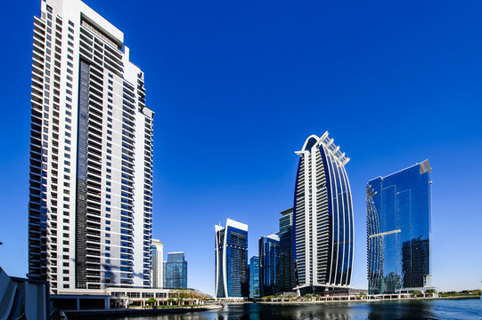 Business Bay, Dubai, United Arab Emirates - 02/12/2015: Skate Park Young Filipino Male BMX Bike Rider Performing A Flip, Stunt Or Jump With Burj Khalifa In Background With Blue Sky And Clouds