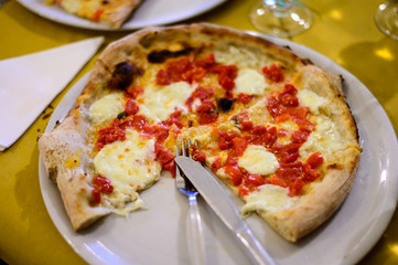 Eating of Italian pizza with mozzarella cheese, small red tomatoes and fresh basil