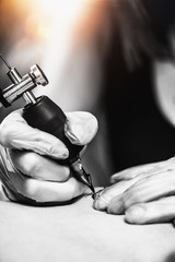 Hand of Tattooist in Rubber Gloves Drawing a Tattoo with Electric Tattoo Gun Close-up