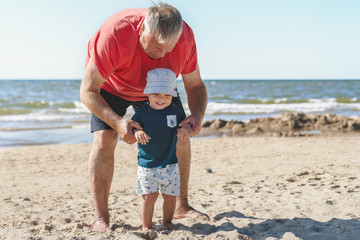 Grandpa and grandson happy together in sandy Baltic sea beach. Two different generations. Family vacation and lifestyle concept.