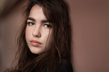 Fototapeta premium Young woman near wall and looks at the camera