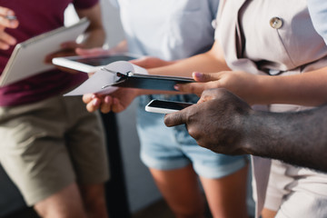 Cropped view of business people working with smartphone and clipboard in office