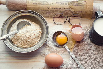 Flour and eggs on wooden table as ingredients for traditional bread baking on granny's recipe