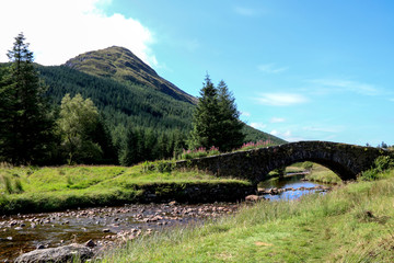 Old Stone Bridge Over a Highland River with Mountain Behind