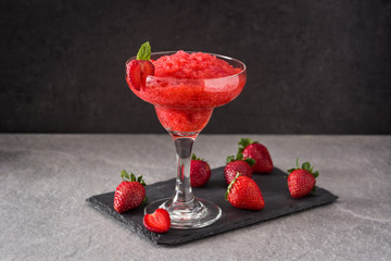 Strawberry margarita cocktail in glass on black background	