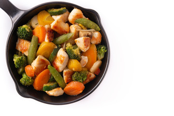 Stir fry chicken with vegetables on iron pan isolated on white background. Top view. Copy space