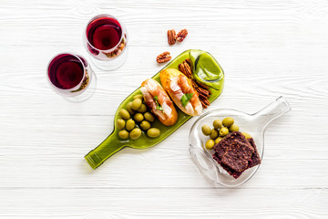Toasts with prosciutto and tomatoes on glass bottle plate with red wine top view