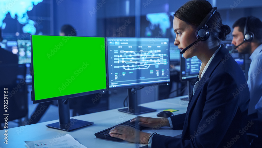 Aufkleber Confident Female Data Scientist Works on Personal Computer with Green Screen Mock Up in Big Infrastructure Control and Monitoring Room. Woman Engineer in Headset in Call Center Office with Colleagues.