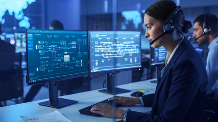 Confident Female Data Scientist Works on Personal Computer Wearing a Headset in Big Infrastructure...