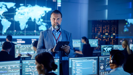 Male Project Leader is Standing with Tablet Computer and Checking Work Data. Science Engineers Work...
