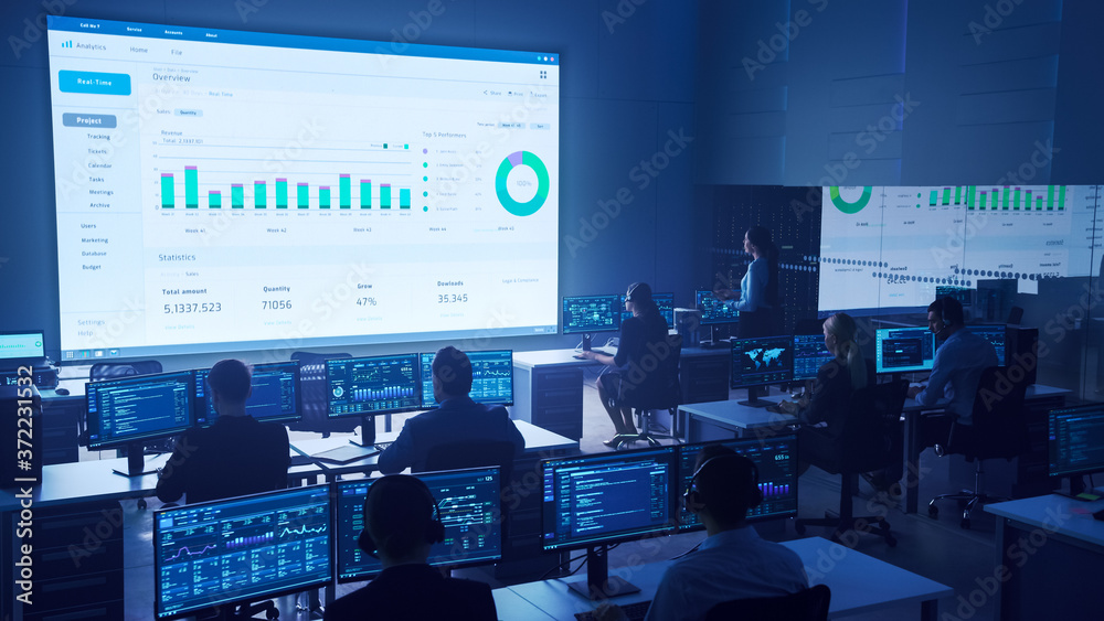 Aufkleber Team of Professional Big Data Business Traders Work on Desktops with Screens Showing Charts, Graphs, Infographics, Technical Neural Data and Statistics. Low Key Control and Monitoring Room.