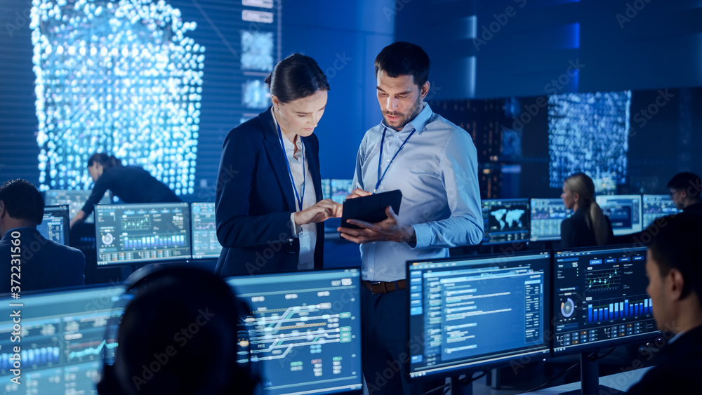 Poster Project Manager and Computer Science Engineer Talking while Using A Digital Tablet Computer. Telecommunications Company System Control and Monitoring Office Room with Working Specialists.