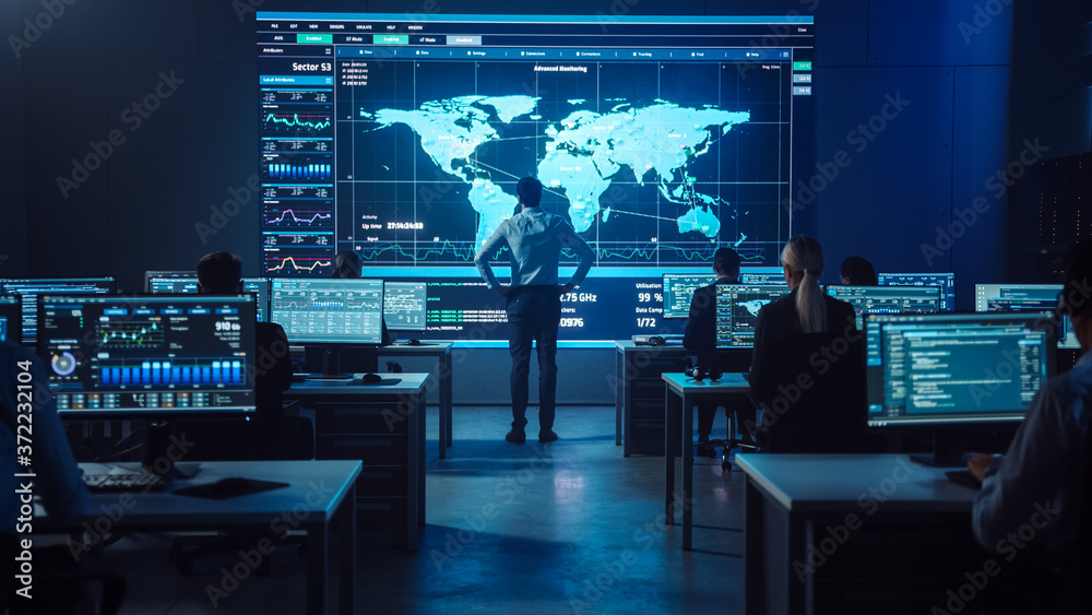 Poster Project manager Stands Next to Big Screen with Neural Network. Team of Professional Computer Data Science Engineers Work on Desktops in a Dark System Control and Monitoring Telecommunications Office.