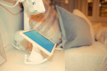 A tablet with a green screen sits near the bed, hospital bed.