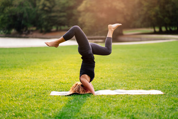 one young fit blond woman doing yoga alone outdoor at the park at sunset time