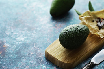 Avocado cooking recipes. Ripe green avocado on a wooden cutting board for serving.