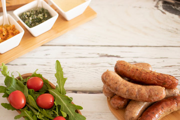 Grilled sausages with spices and sauces on the table with salad