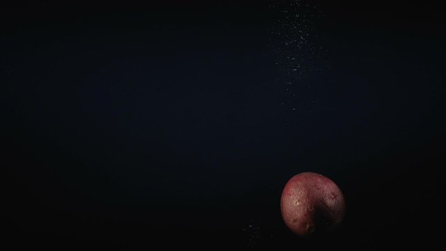 Video of falling maracuya in the water on black background