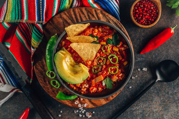 Chili Con Carne in bowl with tortilla chips on dark background. Mexican cuisine.