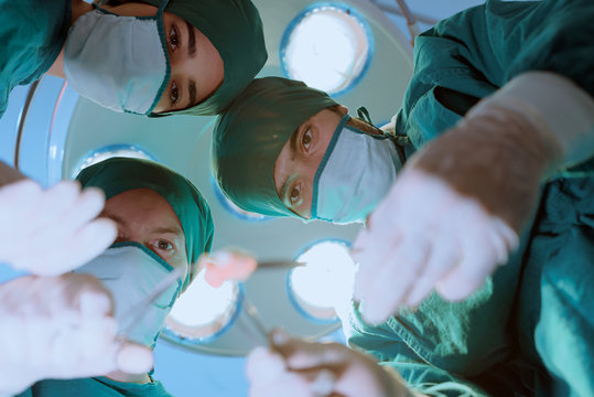 Group Of Surgeons Doing Surgery In Hospital Operating Theater. Medical Team Doing Critical Operation.