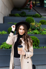 Coffee on the go. Beautiful young woman holding coffee cup and smiling while walking along the street