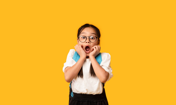 Shocked Japanese Schoolgirl Posing With Opened Mouth, Yellow Studio Background