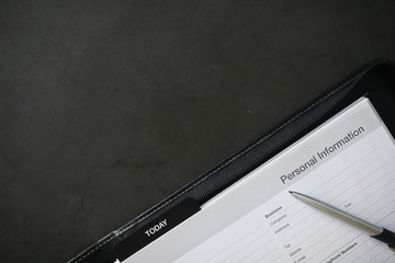 Filling out a form with personal information. Documents in a folder on the table to fill....