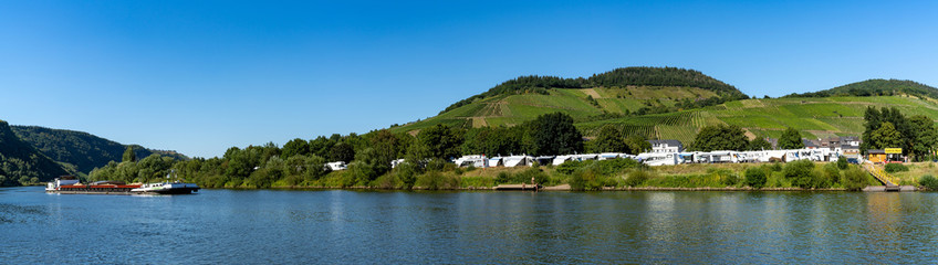 Fototapeta na wymiar panorama of a river barge travelling up the Mosel River with an RV campground behind