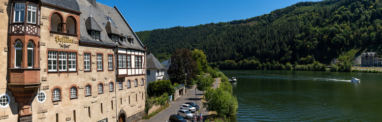 Fototapeta na wymiar view of the historic post office in Traben-Trarbach and the Mosel River with a boat headed upstream