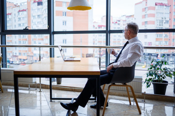 Adult male manager businessman worked successfully and at the end of the day drinks coffee without...