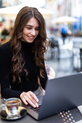 Young charming female freelancer thinking about new ideas during work on laptop computer in outdoors cafe