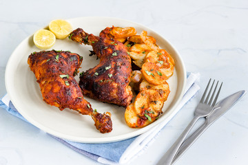 Portuguese Style Roasted Chicken Legs with Potatoes on a Plate with Knife and Fork Horizontal Photo