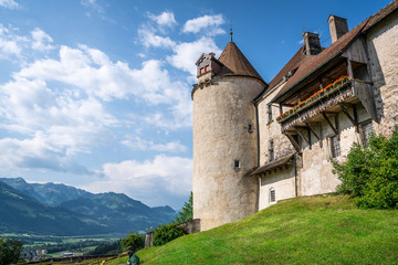 Fototapeta na wymiar Gruyeres medieval castle details view with balcony tower and garden and mountains in background in La Gruyere Switzerland
