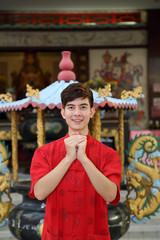 Young south east asian Chinese man traditional costume hand gesture greeting thanks welcome outdoors at temple