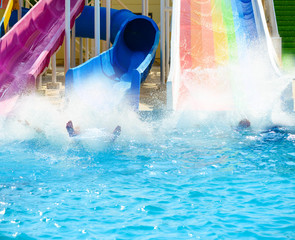 big splashes from people sliding down in pool at summer aqua park action