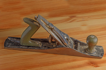 Side view of an old hand plane on a wooden surface close up