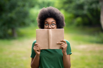 Bookworm. Funny African American Student Girl Standing Outdoors Covering Face With Book