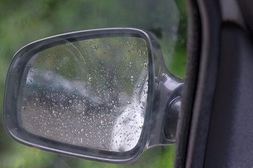 View from the window on the rearview mirror of a car in rainy weather