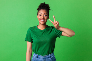 Excited afro girl showing v sign looking at camera