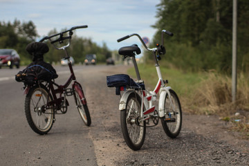 Two bicycles standing on an asphalt road in summer